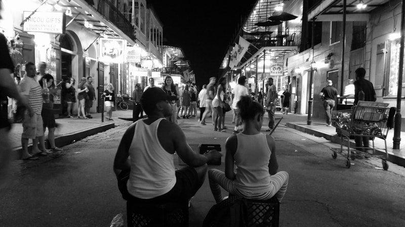 Brother and sister sitting in the middle of Bourbon Street, New Orleans